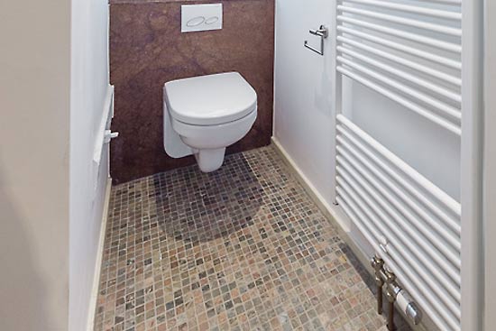 Toilette mit Brown Chocolate als Sanblock-Verkleidung und Copper-Mosaik auf dem Boden.